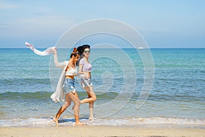 Portrait of two young female friends walking on sea shore happily