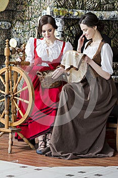 Portrait of Two Young Girls Posing With Old Wooden Spinning Wheel in Retro Dress In Rural Environment
