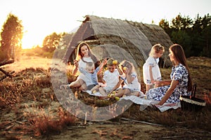 Portrait of a two young mothers with pleasure spending time with her four precious kids on picnic in the summer park