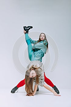 Portrait of two young women in bright red and blue tights and coat posing over grey studio background. Weirdness. Vivid