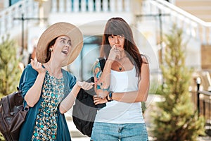 Portrait of a two young women chat on the street. One woman listens boringly to the story of an overly emotional interlocutor. The