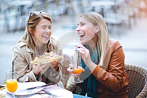 Portrait of two young women eating pizza outdoors