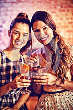 Portrait of two young women having cocktail drinks