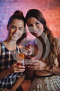 Portrait of two young women having cocktail drinks