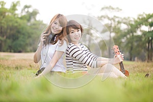 Portrait two young women on the nature of the ukulele