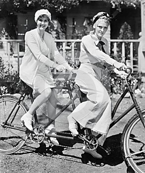 Portrait of two young women sitting on a tandem bicycle