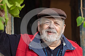 Portrait of Ukrainian bearded smiling senior peasant against old barn entry