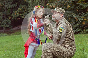 Portrait of a Ukrainian little girl with her military father in the park