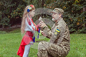 Portrait of a Ukrainian little girl with her military father in the park