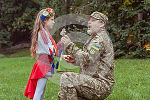 Portrait of a Ukrainian little girl with her military father in the park