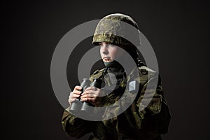 Portrait of unarmed woman with camouflage. Young female soldier observe with binoculars.