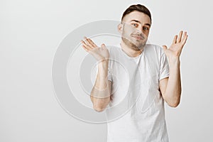 Portrait of unaware careless and indifferent handsome male student in white t-shirt with beard and moustache raising