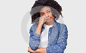 Portrait of uncertain African American woman has puzzled expression, frowns her face and looking up. Doubtful dark skinned female