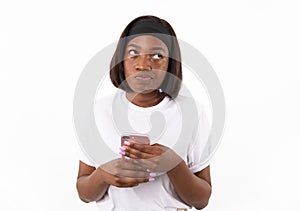 Portrait of uncertain young woman holding mobile phone