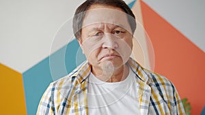 Portrait of unhappy Asian mature man looking at camera with depressed expression