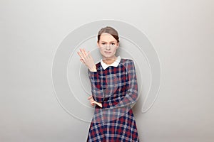 Portrait of unhappy bewildered young blond woman raising one hand