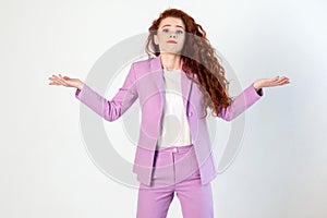 Portrait of unhappy confused business woman with red - brown hair and makeup in pink suit. looking at camera