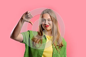 Pretty woman with sign of dislike. Young millennial girl showing thumbs-down photo