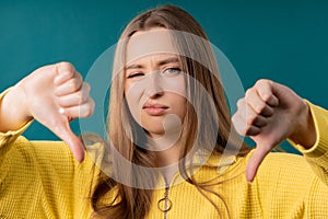 Pretty woman with sign of dislike. Young millennial girl showing thumbs-down photo