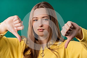 Pretty woman with sign of dislike. Young millennial girl showing thumbs-down photo