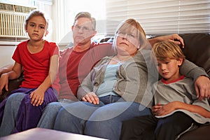 Portrait Of Unhappy Family Sitting On Sofa Together