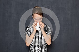 Portrait of unhappy girl blowing her nose in handkerchief