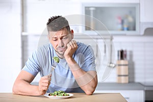 Portrait of unhappy man eating broccoli salad