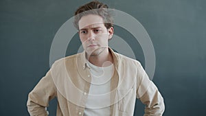 Portrait of unhappy man looking at camera with worried facial expression standing on gray background