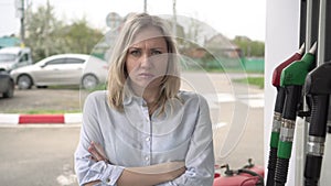 Portrait of an unhappy sad man at a gas station. An upset woman in front of a gas station. Rising fuel prices