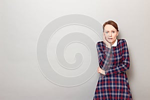 Portrait of unhappy shocked frightened girl touching cheek with hand