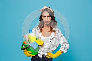 Portrait of unhappy upset housemaid 20s wearing yellow rubber gloves for hands protection holding bucket with cleaning