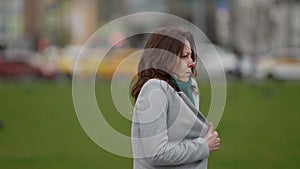 portrait of unhappy woman outdoors, lady is wrapping in jacket, feeling cold wind, medium shot