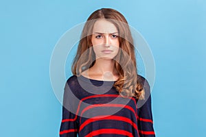 Portrait of unhappy woman wearing striped casual style sweater standing looking at camera, having