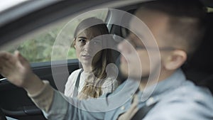 Portrait of unhappy young Caucasian woman sitting on passenger seat talking to man driving. Dissatisfied beautiful