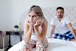 Portrait of unhappy young couple in bedroom