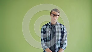 Portrait of unhappy young man looking at camera standing on green background