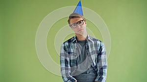 Portrait of unhappy young man in party hat looking at camera with sad face