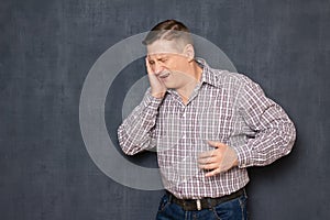 Portrait of unhappy young man suffering severe toothache