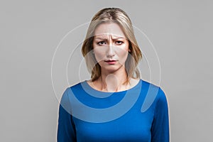 Portrait of unhappy young woman frowning and worrying about failure. indoor studio shot isolated on gray background