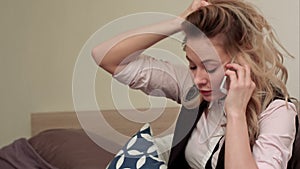 Portrait of unhappy young woman making annoyed phone call at home