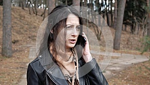 Portrait of unhappy young woman is talking on phone outdoors angry