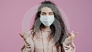 Portrait of unhappy young woman wearing face mask gesturing during covid-19 pandemic