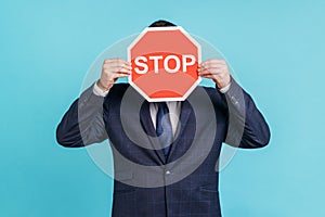 Portrait of unknown man office worker wearing official style suit hiding his face behind red stop