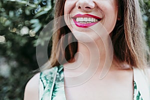 Portrait of unrecognizable young woman smiling at sunset. Red lips and beautiful smile. Happiness concept