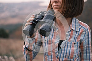 Portrait of an unrecognizable young woman traveler with binoculars in her hands.