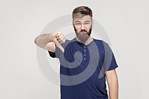 Portrait of unsatisfied bearded man with thumbs down