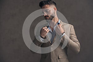 Portrait of unshaved businessman with glasses arranging jacket