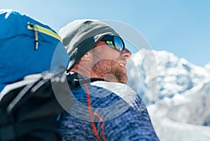 Portrait of unshaved Hiker man with backpack and UV protecting sunglasses on Taboche 6495m peakk background ,  He enjoying photo