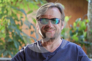 Portrait of an unshaven middle-aged man in sunglasses relaxing on the nature in summer day