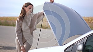 Portrait of unsure worried woman at open car hood with senior man entering and lady asking for help. Caucasian anxious